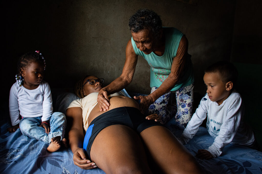 Midwife María Dey Bejarano performs a series of massages on Leidy Catalina Camacho, 23, while her granddaughter (on the far left of the photo) Briana Sofía and Simón, Leidy's first-born, observe the procedure. María Dey, who has attended more than 120 births in Quinamayó, is the last traditional midwife in the town. 